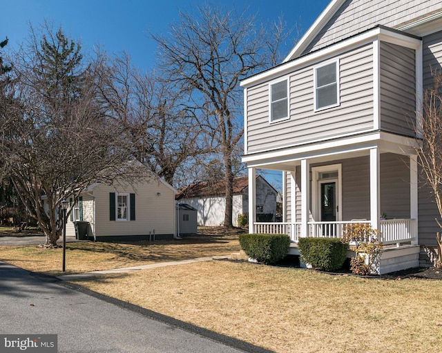 view of side of home featuring covered porch and a lawn