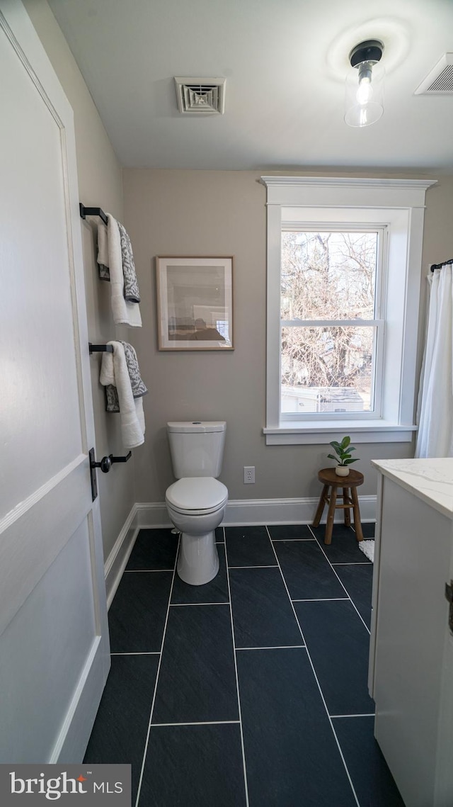 bathroom featuring toilet, tile patterned flooring, visible vents, and baseboards