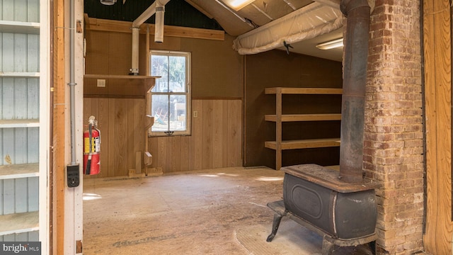 below grade area featuring a wood stove, wood walls, and wainscoting