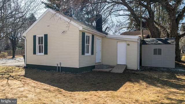 view of home's exterior with entry steps, a shed, and an outbuilding