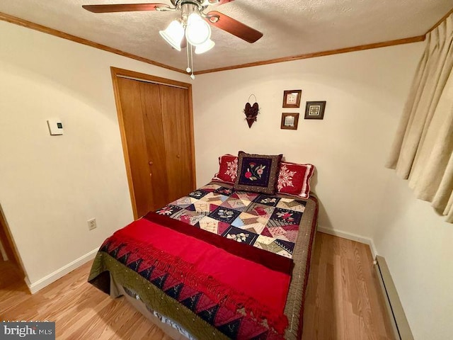 bedroom with crown molding, a textured ceiling, baseboard heating, and wood finished floors