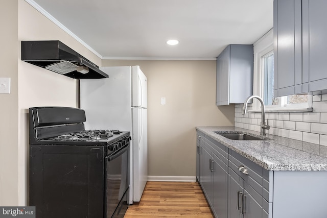 kitchen with gray cabinets, decorative backsplash, black range with gas cooktop, a sink, and exhaust hood