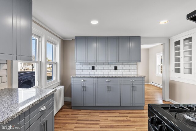 kitchen featuring light wood-style floors, baseboard heating, backsplash, and gray cabinetry