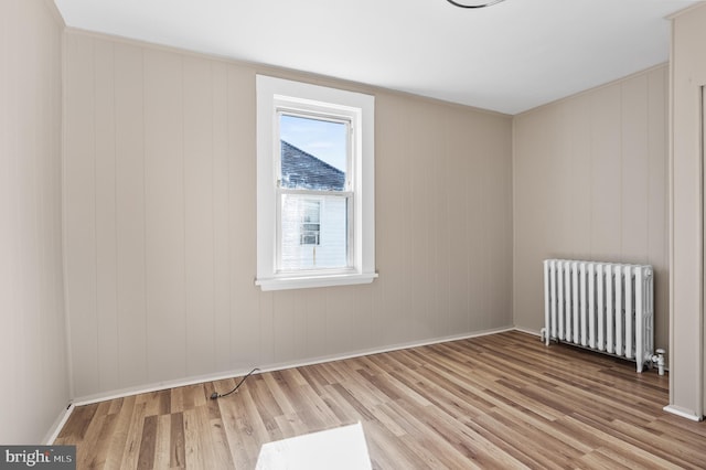 spare room with radiator heating unit, baseboards, and wood finished floors