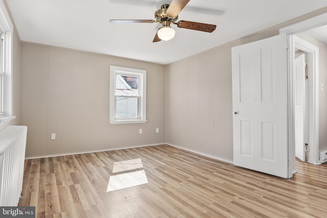 unfurnished bedroom with a ceiling fan, radiator, and light wood finished floors