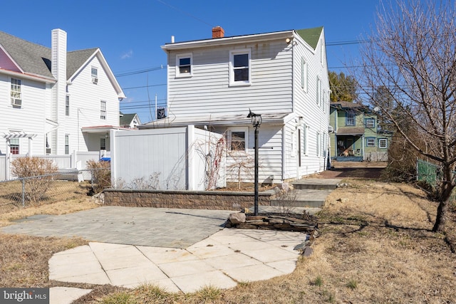 rear view of house featuring a patio area, a chimney, and fence