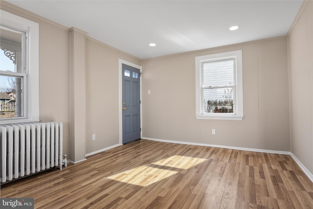 spare room featuring radiator, baseboards, wood finished floors, and ornamental molding