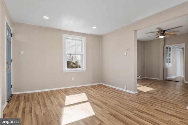 spare room featuring a ceiling fan, crown molding, baseboards, and wood finished floors