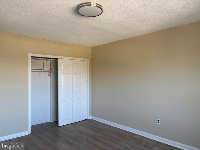 unfurnished bedroom with a closet, baseboards, dark wood-type flooring, and a textured ceiling