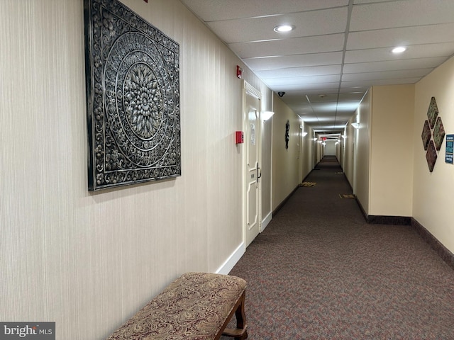 hall with dark carpet, recessed lighting, baseboards, and a drop ceiling