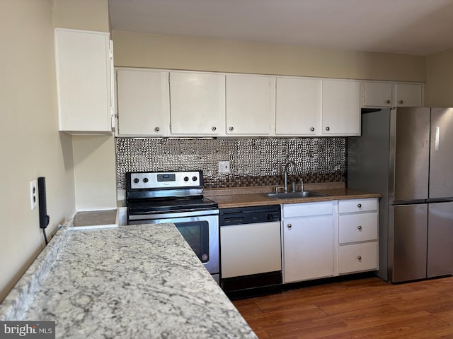 kitchen with a sink, decorative backsplash, appliances with stainless steel finishes, white cabinetry, and dark wood-style flooring