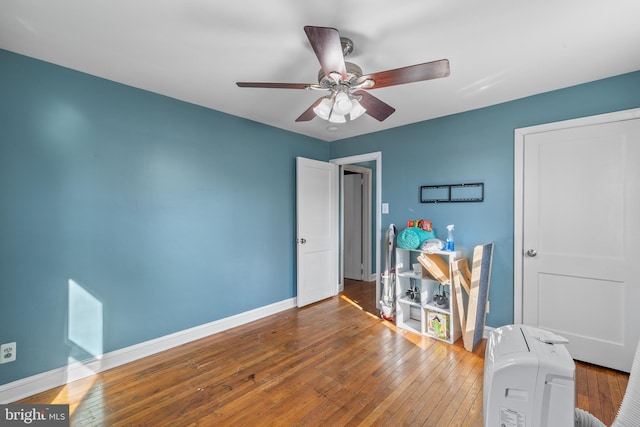 interior space featuring ceiling fan, baseboards, and hardwood / wood-style flooring