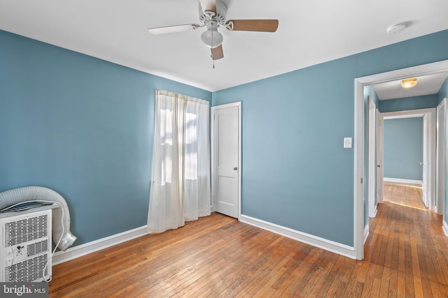 unfurnished bedroom with a closet, baseboards, a ceiling fan, and hardwood / wood-style flooring