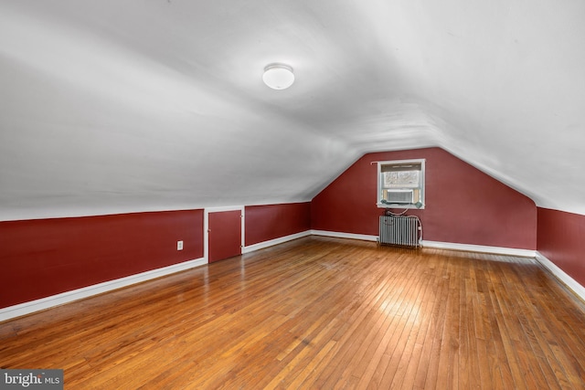 bonus room with radiator, lofted ceiling, baseboards, and hardwood / wood-style flooring