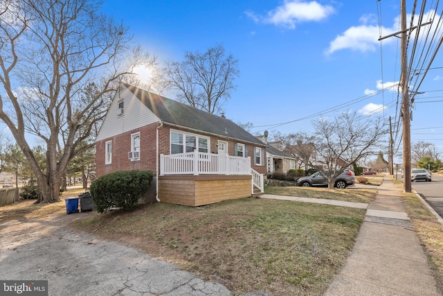 view of front of home with cooling unit, brick siding, a chimney, and a front lawn