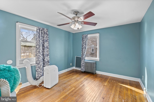 sitting room with hardwood / wood-style flooring, radiator heating unit, a ceiling fan, and baseboards