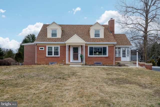 new england style home featuring brick siding, roof with shingles, a chimney, and a front lawn