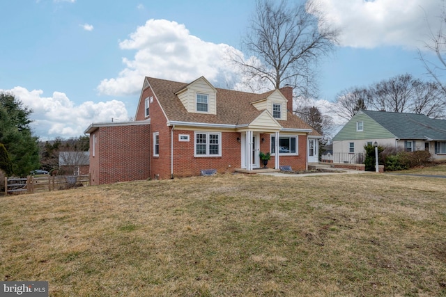 cape cod-style house with brick siding, a front lawn, a chimney, and fence