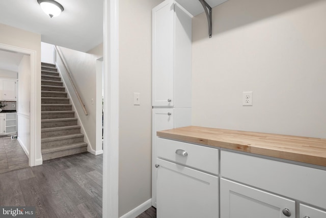 bar with stairs, dark wood finished floors, and baseboards