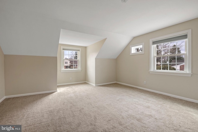 additional living space featuring carpet, baseboards, and vaulted ceiling