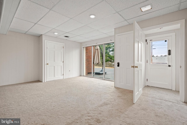 interior space with carpet floors, access to outside, and a drop ceiling