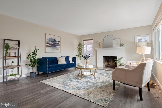 living area with a fireplace, baseboards, and dark wood finished floors