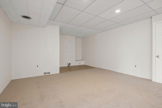 carpeted empty room featuring visible vents and a drop ceiling