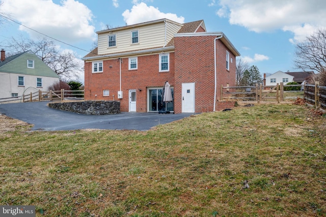 back of property featuring a yard, fence, a patio, and brick siding