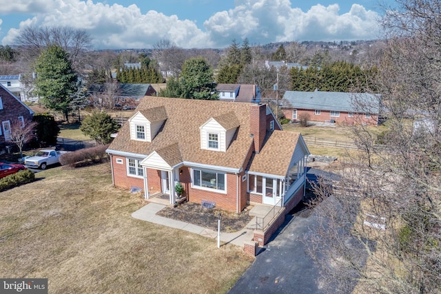 view of front facade featuring brick siding, roof with shingles, a front lawn, and aphalt driveway