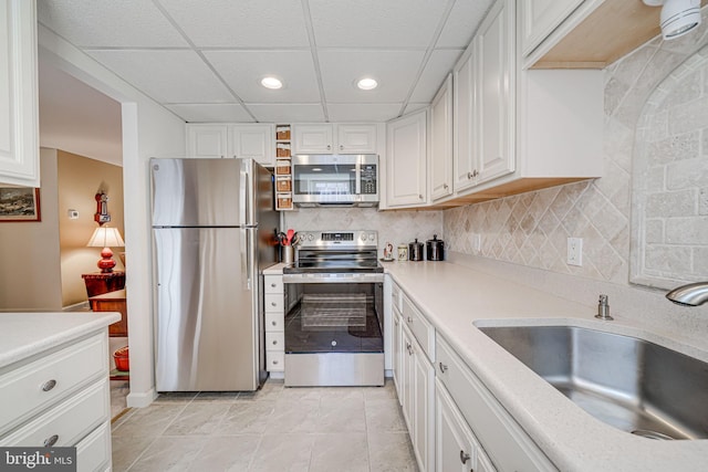 kitchen with a sink, tasteful backsplash, white cabinetry, appliances with stainless steel finishes, and light countertops