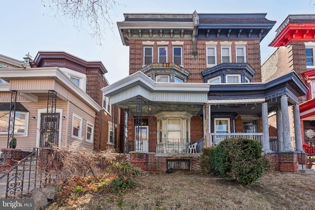 view of front facade featuring brick siding and a porch