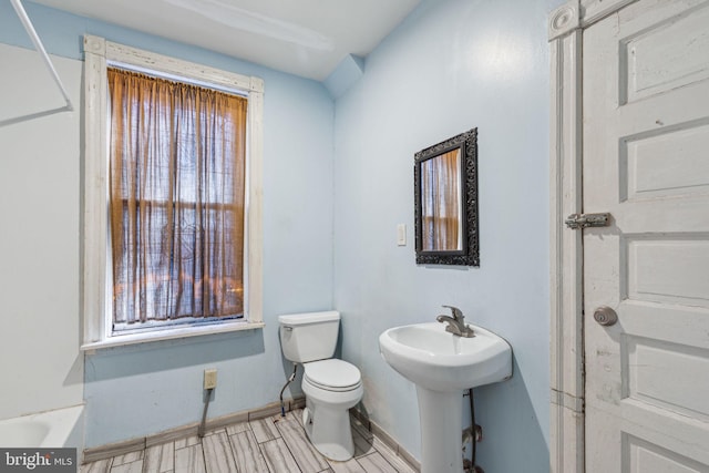 bathroom with wood finished floors, toilet, and baseboards