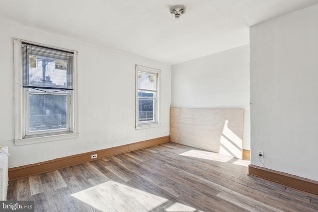 spare room with baseboards and wood finished floors