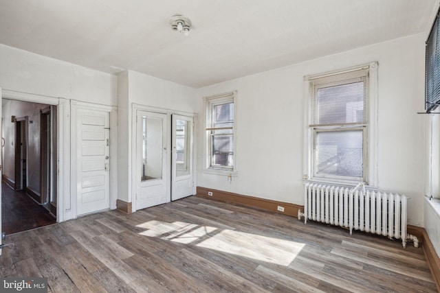 unfurnished bedroom with radiator, baseboards, and wood finished floors