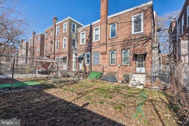 rear view of house with brick siding and fence