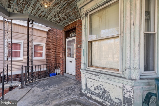 view of exterior entry featuring a porch and brick siding