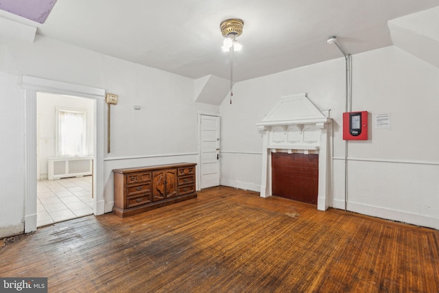 unfurnished living room featuring lofted ceiling, hardwood / wood-style floors, and radiator