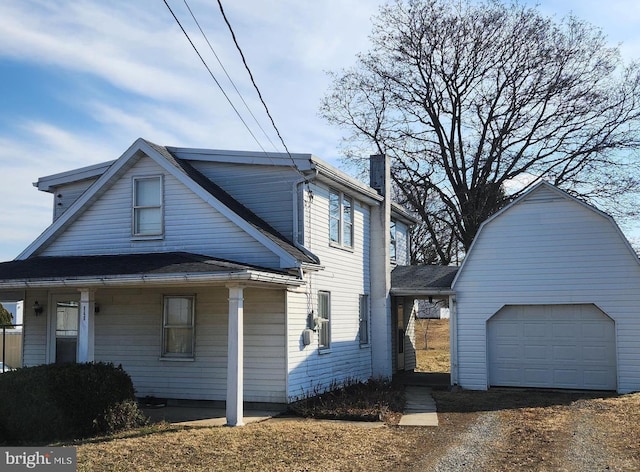 view of front of home with an outbuilding, a chimney, and a detached garage