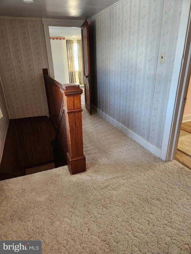 hall with wallpapered walls, an upstairs landing, baseboards, and carpet floors