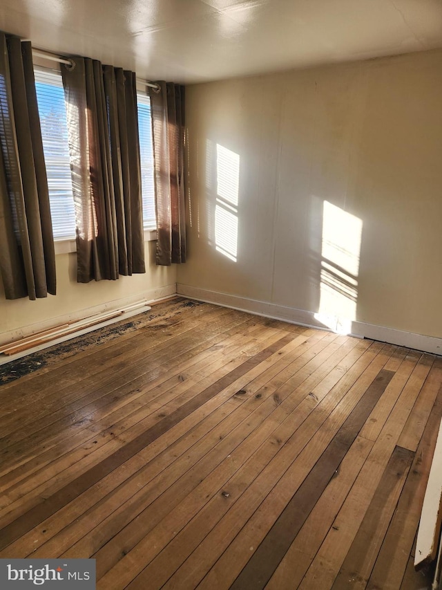 spare room with a healthy amount of sunlight, baseboards, and hardwood / wood-style floors