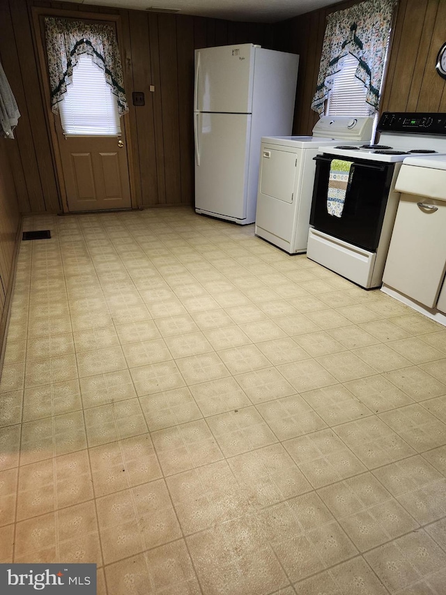 kitchen with light countertops, wooden walls, washer / clothes dryer, and freestanding refrigerator