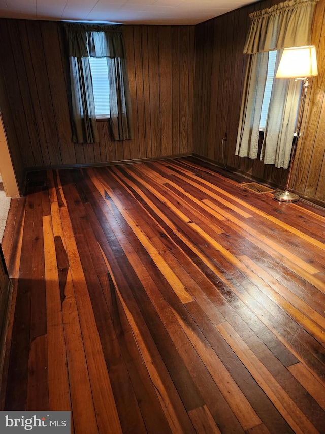 empty room featuring dark wood-type flooring and wooden walls