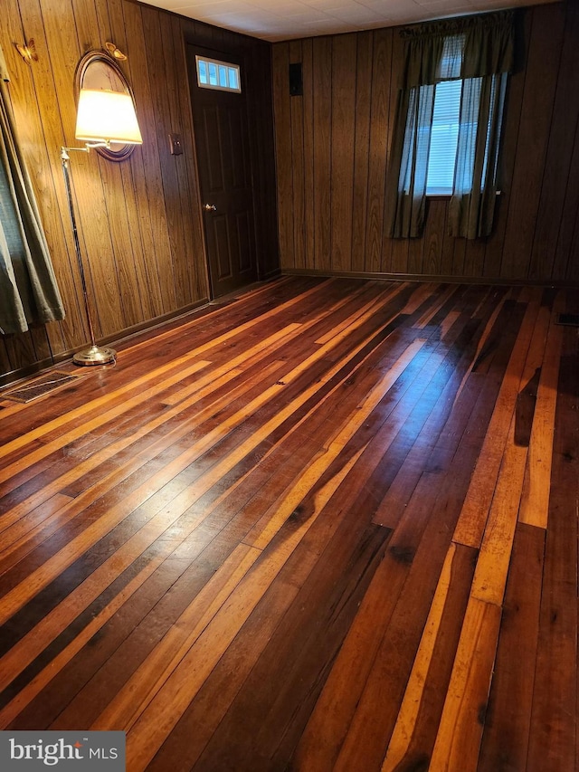 spare room featuring wooden walls and dark wood-style flooring