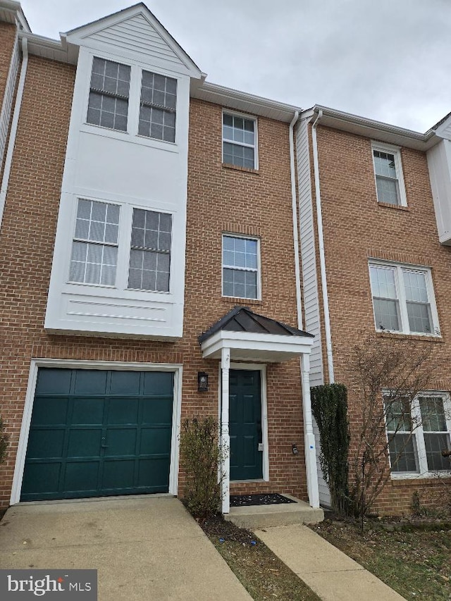 multi unit property featuring a garage, driveway, and brick siding