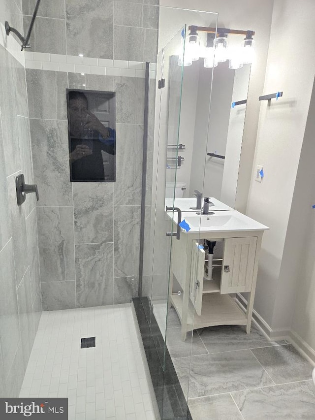 bathroom featuring a stall shower, vanity, and baseboards