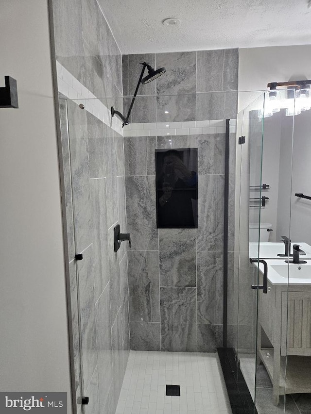 bathroom with a shower stall, a textured ceiling, and vanity