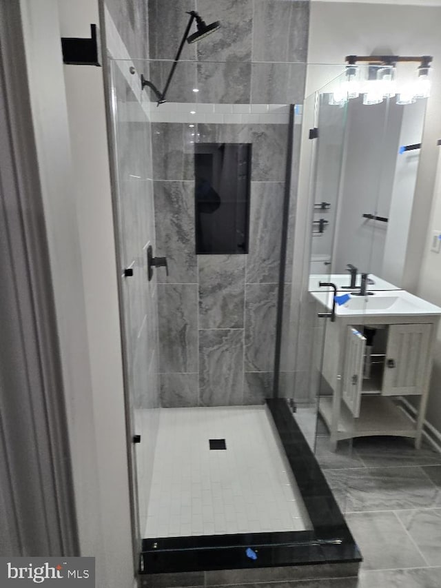 bathroom with marble finish floor, a tile shower, and vanity