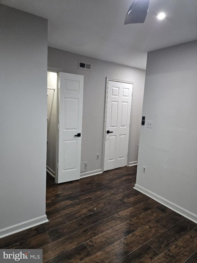 empty room featuring wood finished floors, visible vents, and baseboards