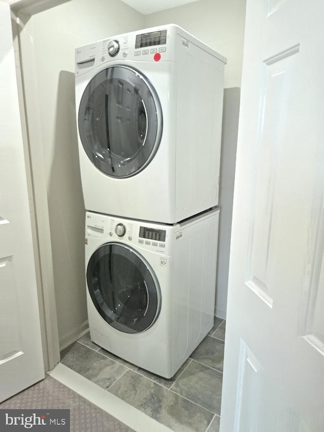 laundry room featuring laundry area, stacked washer / dryer, and tile patterned floors