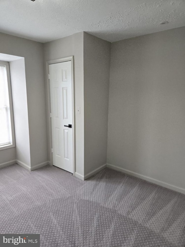 interior space with a textured ceiling, carpet, and baseboards